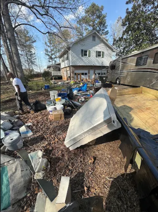 Household items and debris spread across a yard before a Big Kountry cleanout